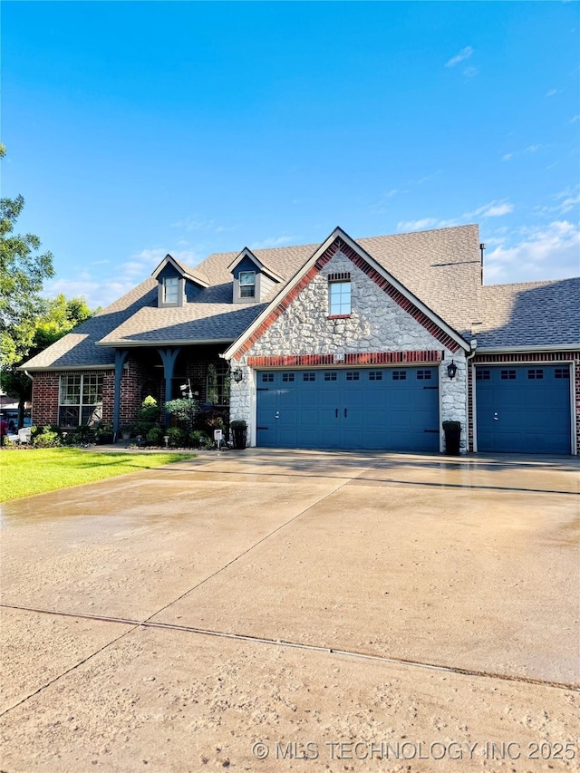 traditional-style home with an attached garage, concrete driveway, roof with shingles, stone siding, and brick siding