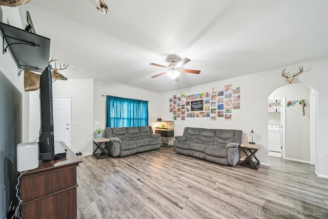 living area with wood finished floors, arched walkways, ceiling fan, and baseboards