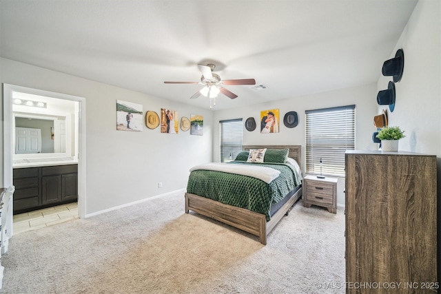 bedroom with light carpet, ensuite bathroom, baseboards, and ceiling fan
