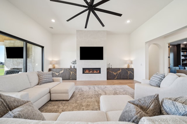 8499 S Timber Wolf Dr, Broken Arrow, OK 74014 - living room featuring a large fireplace, a ceiling fan, wood finished floors, arched walkways, and recessed lighting