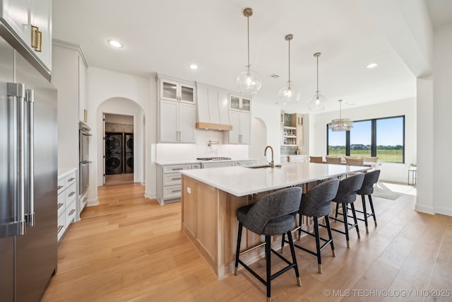 8499 S Timber Wolf Dr, Broken Arrow, OK 74014 - kitchen with appliances with stainless steel finishes, arched walkways, light wood-style flooring, washer and clothes dryer, and recessed lighting