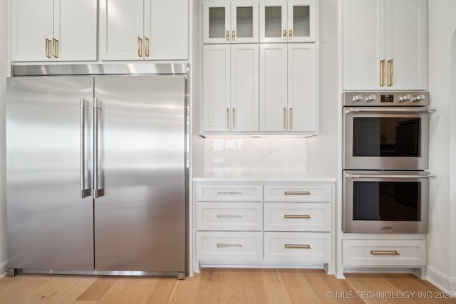 8499 S Timber Wolf Dr, Broken Arrow, OK 74014 - kitchen with appliances with stainless steel finishes, light countertops, glass insert cabinets, white cabinetry, and light wood-style floors