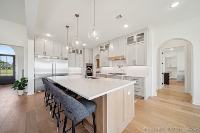 8499 S Timber Wolf Dr, Broken Arrow, OK 74014 - kitchen with appliances with stainless steel finishes, arched walkways, light wood-type flooring, a sink, and recessed lighting