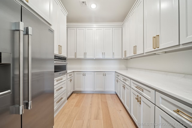 8499 S Timber Wolf Dr, Broken Arrow, OK 74014 - kitchen featuring stainless steel appliances, light wood-style floors, white cabinetry, recessed lighting, and light stone countertops