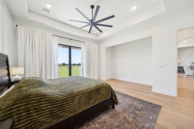 8499 S Timber Wolf Dr, Broken Arrow, OK 74014 - bedroom with a raised ceiling, arched walkways, light wood-type flooring, baseboards, and recessed lighting