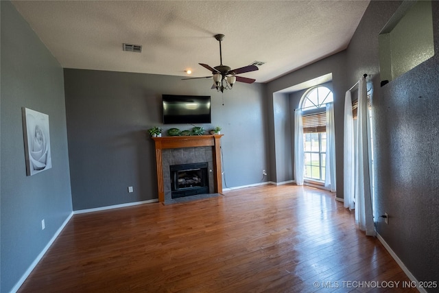 11636 S 102nd E Ave, Bixby, OK 74008 - unfurnished living room with wood finished floors, ceiling fan, a textured ceiling, a tile fireplace, and baseboards