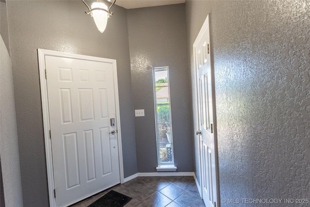 11636 S 102nd E Ave, Bixby, OK 74008 - entryway featuring dark tile patterned floors, a textured wall, and baseboards