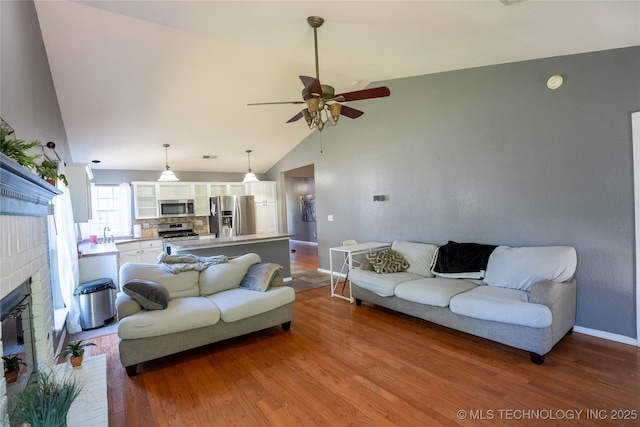 11636 S 102nd E Ave, Bixby, OK 74008 - living area featuring a ceiling fan, vaulted ceiling, wood finished floors, baseboards, and a brick fireplace