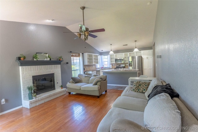 11636 S 102nd E Ave, Bixby, OK 74008 - living area featuring ceiling fan, light wood finished floors, a brick fireplace, high vaulted ceiling, and baseboards
