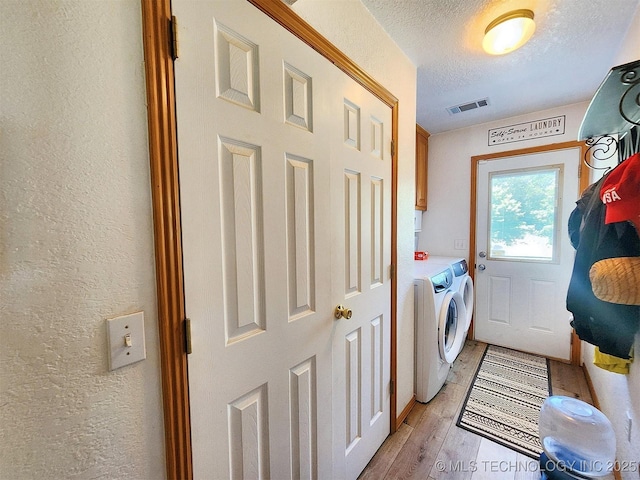 35824 S Talon Dr, Cookson, OK 74427 - clothes washing area featuring washer and clothes dryer, cabinet space, a textured wall, a textured ceiling, and light wood finished floors