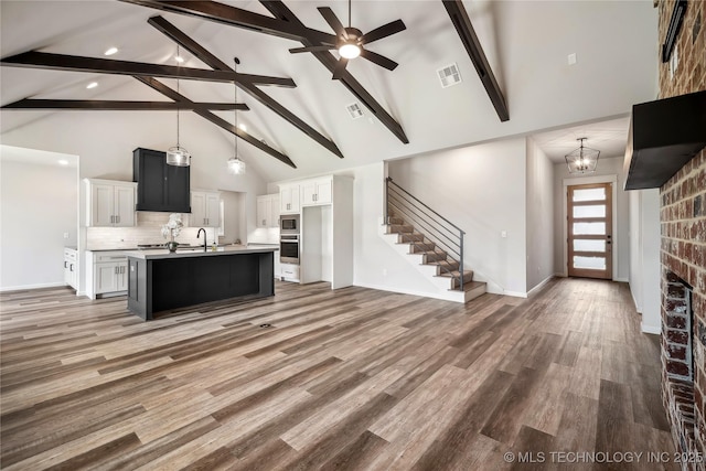 2044 E 138th Pl S, Bixby, OK 74008 - unfurnished living room with high vaulted ceiling, beamed ceiling, stairway, ceiling fan, and a sink
