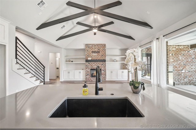 2044 E 138th Pl S, Bixby, OK 74008 - kitchen with a sink, a fireplace, light countertops, and white cabinets