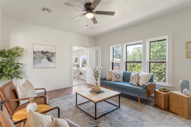living area with baseboards, ornamental molding, and a ceiling fan