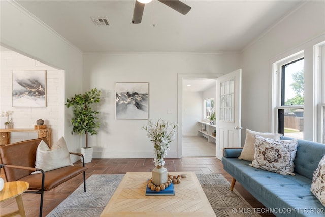 living area with a ceiling fan, ornamental molding, and baseboards
