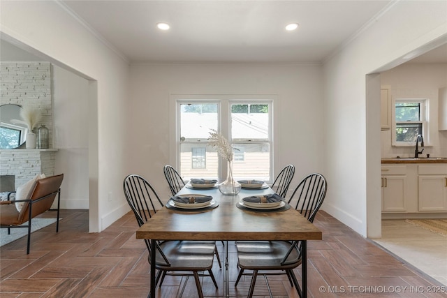 dining area with baseboards, crown molding, recessed lighting, and a stone fireplace