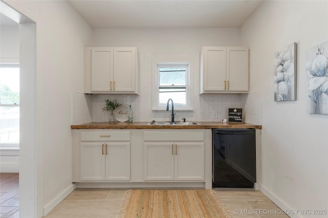 kitchen featuring dishwasher, a sink, decorative backsplash, and baseboards