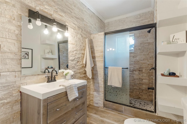 bathroom featuring ornamental molding, a stall shower, vanity, and wood finished floors