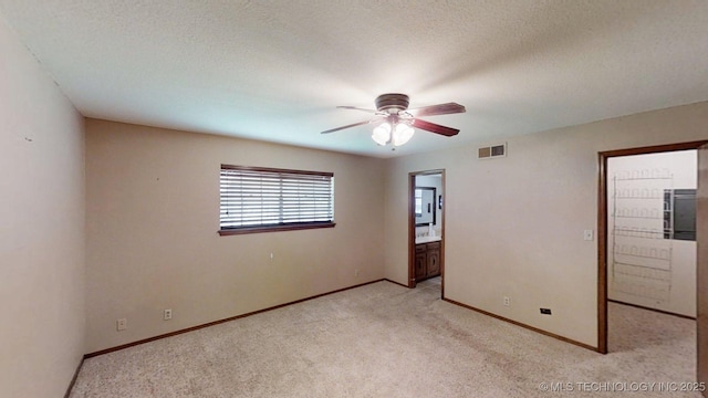 1703 Vaden Ln, Ardmore, OK 73401 - unfurnished bedroom with light colored carpet, baseboards, ensuite bath, a ceiling fan, and a textured ceiling