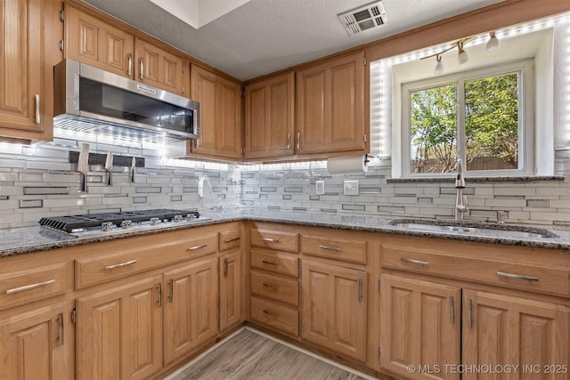 619 S Magnolia Pl, Broken Arrow, OK 74012 - kitchen featuring stainless steel appliances, a sink, dark stone countertops, and backsplash