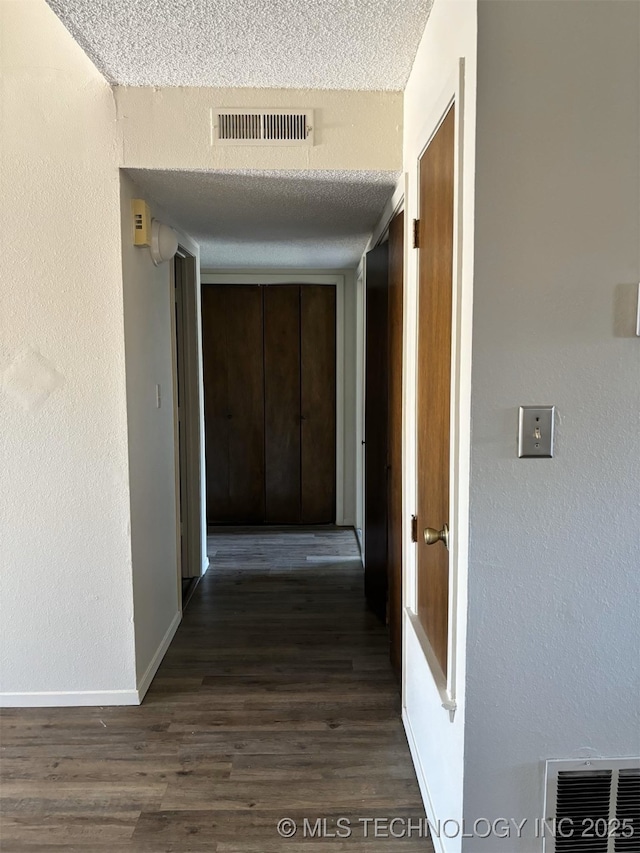 1612 Rustic Dr, Ardmore, OK 73401 - hall with dark wood-style floors, a textured ceiling, baseboards, and a textured wall