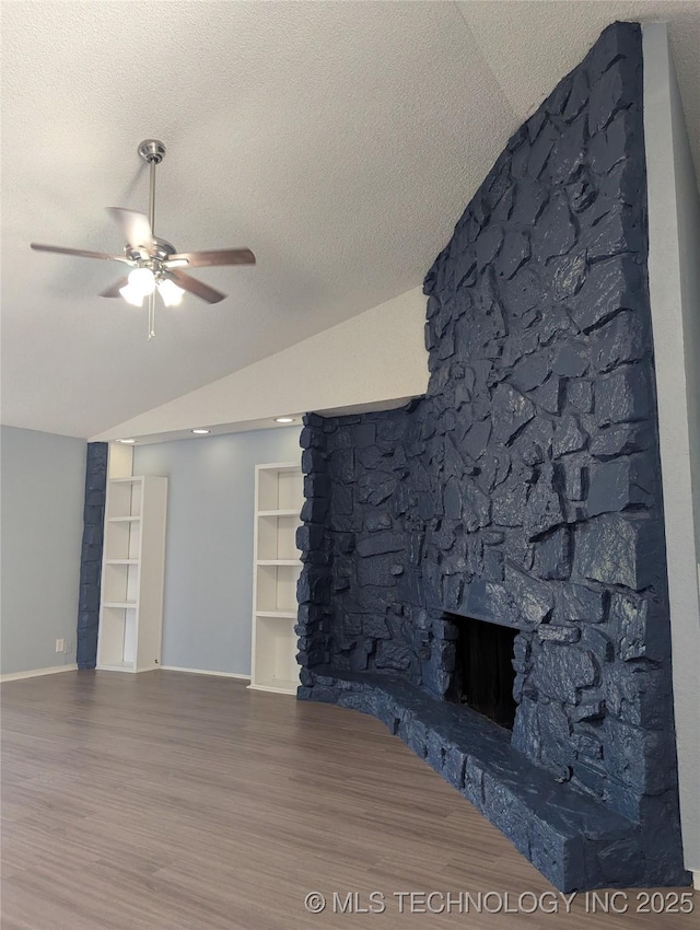 9533 E 136th St, Bixby, OK 74008 - unfurnished living room with wood finished floors, vaulted ceiling, a ceiling fan, a fireplace, and a textured ceiling
