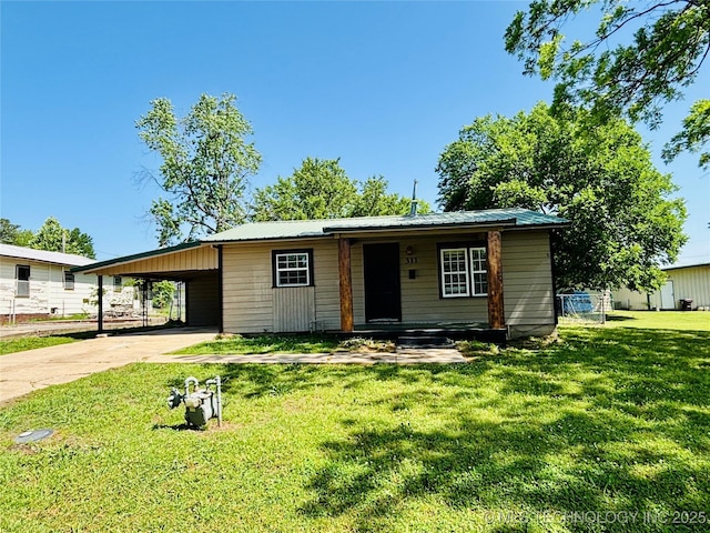 view of front facade featuring driveway, a front lawn, metal roof, a carport, and a porch