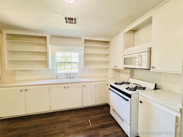 kitchen with open shelves, white appliances, a sink, a textured ceiling, and dark wood-style flooring