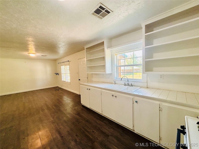 kitchen with open shelves, a sink, a textured ceiling, dark wood finished floors, and white cabinetry