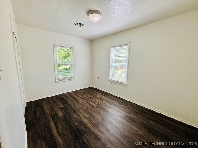 unfurnished room with healthy amount of natural light, dark wood finished floors, and baseboards