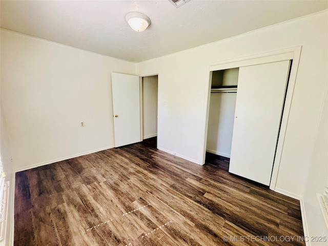 unfurnished bedroom featuring dark wood finished floors, a closet, and baseboards