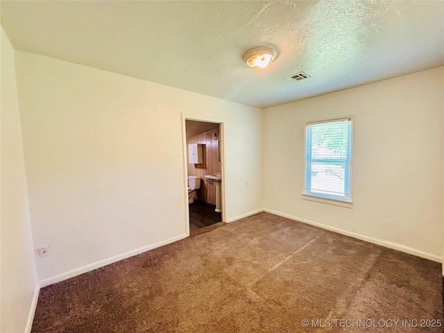 empty room featuring baseboards, carpet, and a textured ceiling