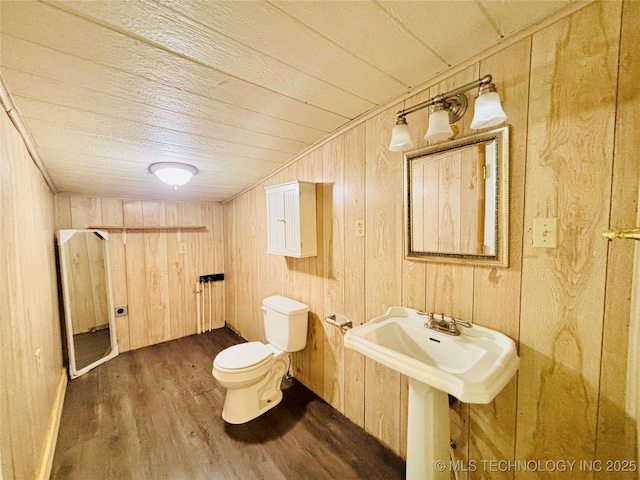 bathroom with wood finished floors, toilet, and wood walls