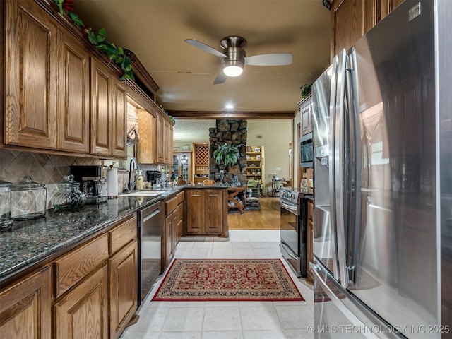 6551 S 41st St E, Muskogee, OK 74403 - kitchen with stainless steel appliances, a peninsula, brown cabinetry, ceiling fan, and light tile patterned flooring