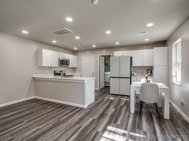 1149 N Hickory Pl, Broken Arrow, OK 74012 - kitchen with stainless steel appliances, baseboards, dark wood finished floors, white cabinets, and a peninsula