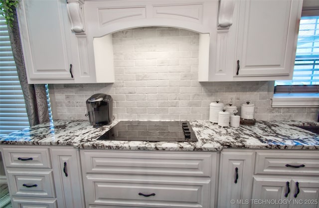 110 W Zachry Ln, Stigler, OK 74462 - kitchen with backsplash, black electric stovetop, white cabinets, and light stone counters