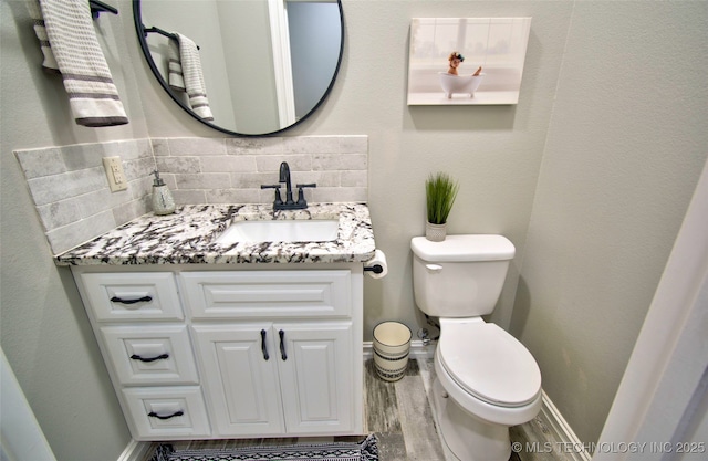 110 W Zachry Ln, Stigler, OK 74462 - half bathroom featuring toilet, wood finished floors, vanity, baseboards, and tasteful backsplash
