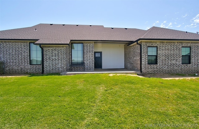 110 W Zachry Ln, Stigler, OK 74462 - back of house featuring brick siding, a patio, roof with shingles, and a yard