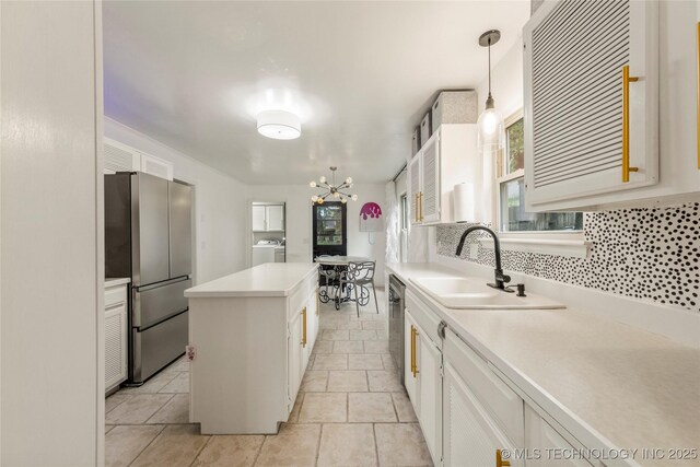 6315 E 98th Pl, Tulsa, OK 74137 - kitchen featuring appliances with stainless steel finishes, washer / dryer, a sink, a center island, and a chandelier