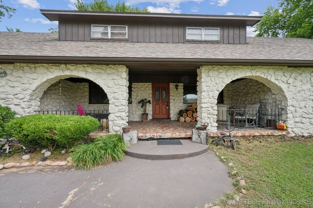 17711 E Archer St, Catoosa, OK 74015 - doorway to property with stone siding, a porch, and board and batten siding