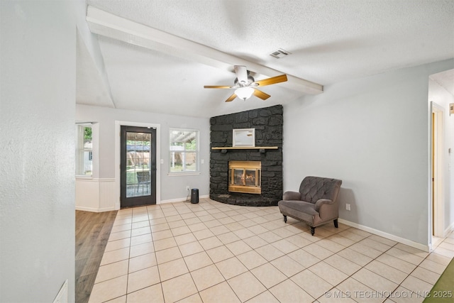 28505 E 139th St S, Coweta, OK 74429 - unfurnished living room featuring a stone fireplace, a textured ceiling, a ceiling fan, light tile patterned flooring, and baseboards