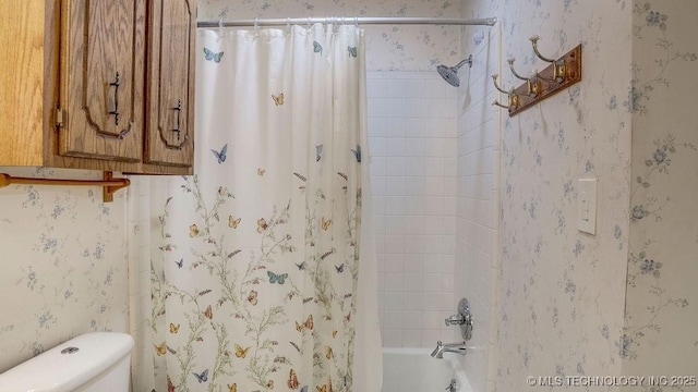 bathroom featuring toilet, wallpapered walls, and shower / bath combination with curtain