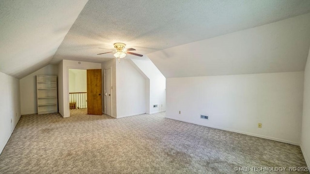 bonus room with vaulted ceiling, carpet, ceiling fan, a textured ceiling, and baseboards
