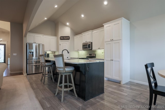 4314 S 132nd E Ave, Tulsa, OK 74134 - kitchen featuring stainless steel appliances, a sink, a center island with sink, light wood-style flooring, and a kitchen bar