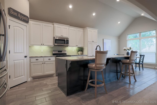 4314 S 132nd E Ave, Tulsa, OK 74134 - kitchen with stainless steel appliances, an island with sink, decorative backsplash, white cabinetry, and a breakfast bar area