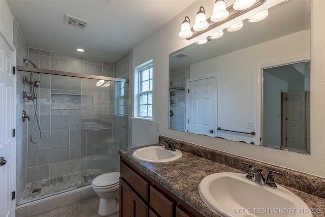 full bath featuring a shower stall, toilet, double vanity, and tile patterned floors