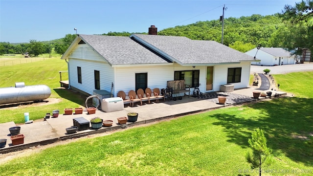 30190 W County Road 1240, Stigler, OK 74462 - back of property featuring a shingled roof, a lawn, a patio area, and a chimney
