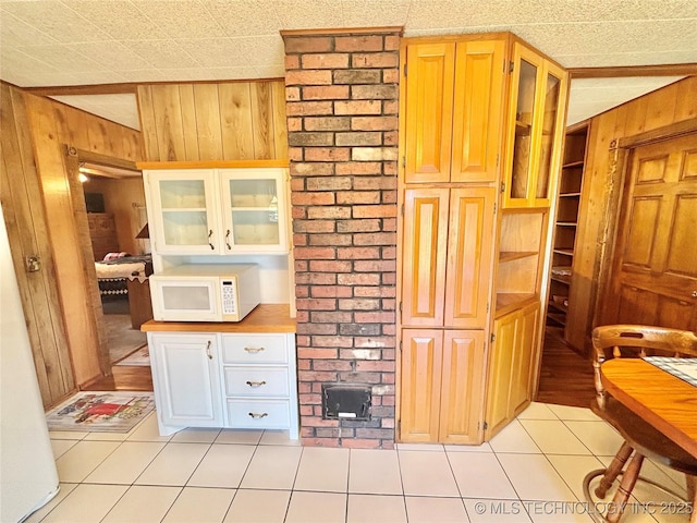 30190 W County Road 1240, Stigler, OK 74462 - kitchen with white microwave, wooden walls, light tile patterned flooring, and glass insert cabinets