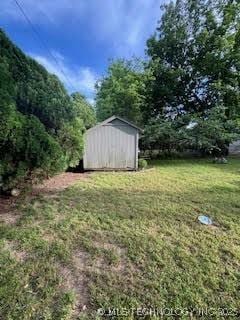 3527 S Knoxville Ave, Tulsa, OK 74135 - view of grassy yard with a storage unit, an outbuilding, and a view of trees