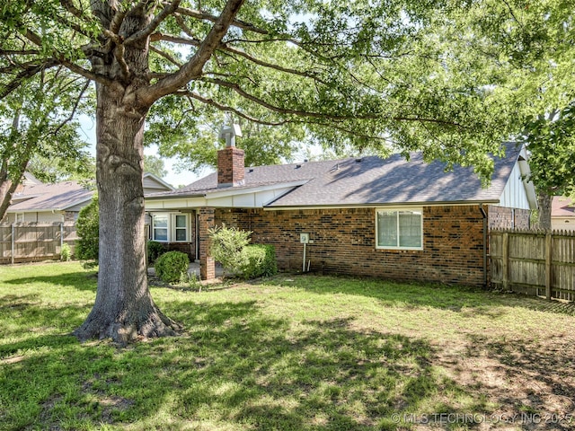 back of house featuring a chimney, brick siding, and roof with shingles