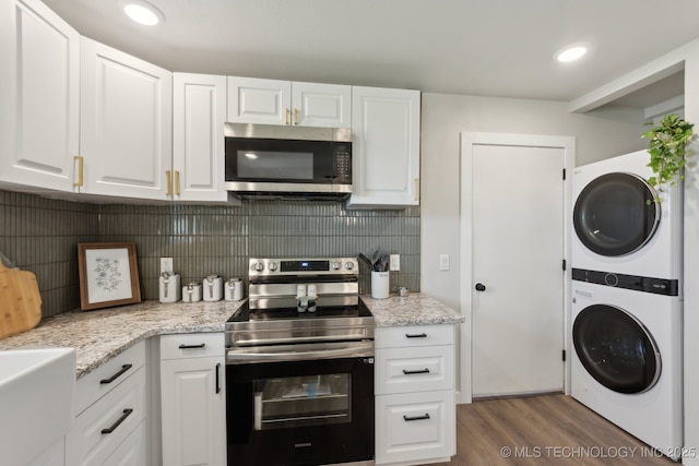 425 Mulberry Ave, Afton, OK 74331 - kitchen featuring appliances with stainless steel finishes, stacked washer and clothes dryer, white cabinetry, wood finished floors, and backsplash